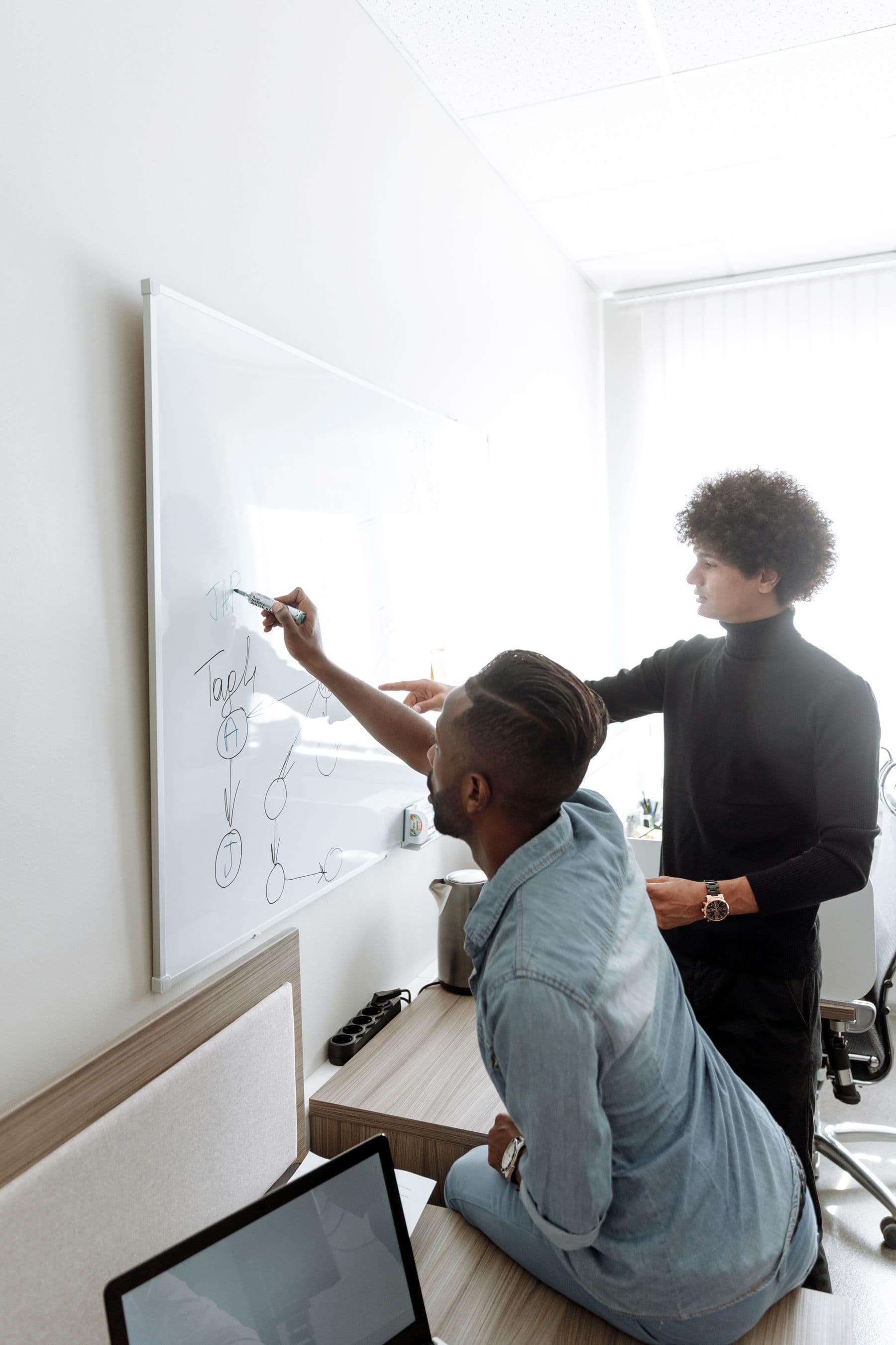 Two men planning a connected workflow on a whiteboard.